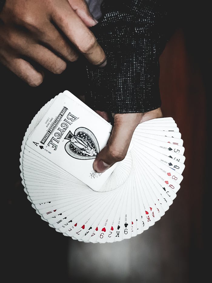 Services Detailed view of a hand displaying a fan of playing cards indoors, focusing on leisure and card games.