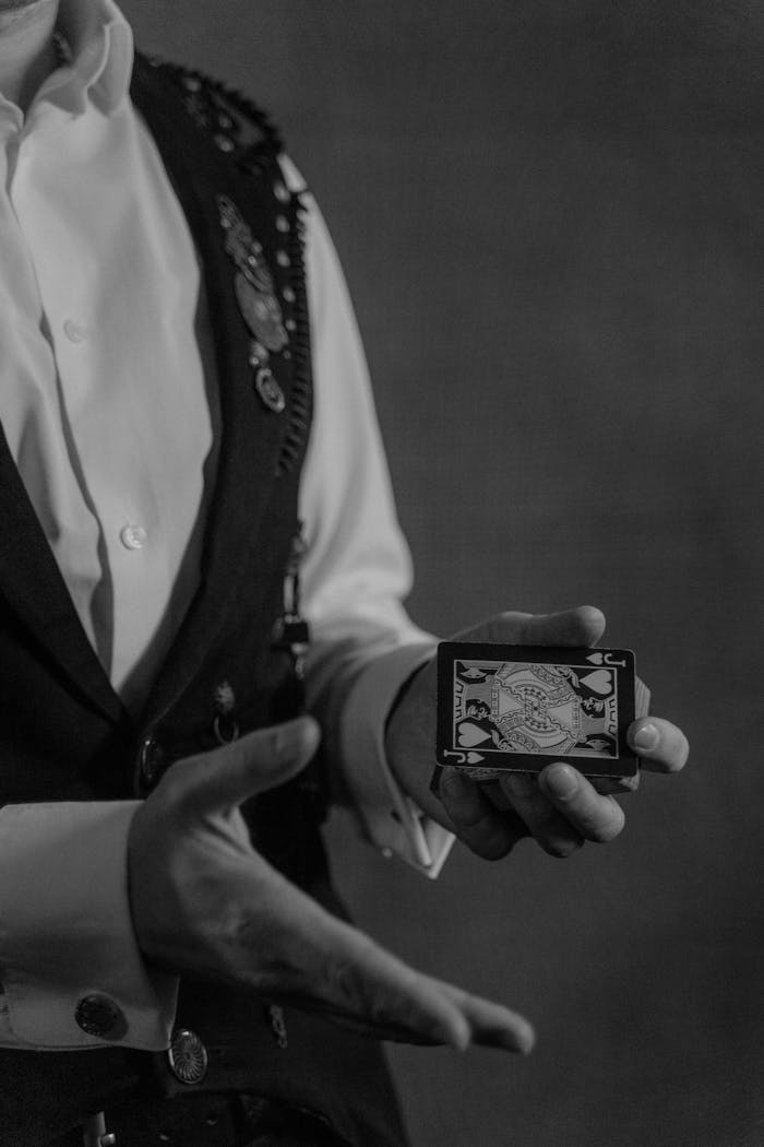 Mastering the First Impression: Your intriguing post title goes here Black and white photo of a magician performing a card trick, showcasing sleight of hand.