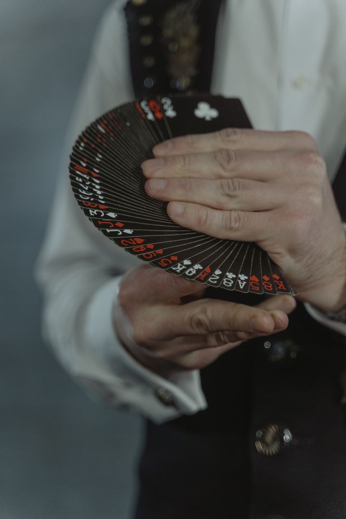 The Art of Drawing Readers In: Your attractive post title goes here An illusionist elegantly displaying a fan of black playing cards during a magic performance.