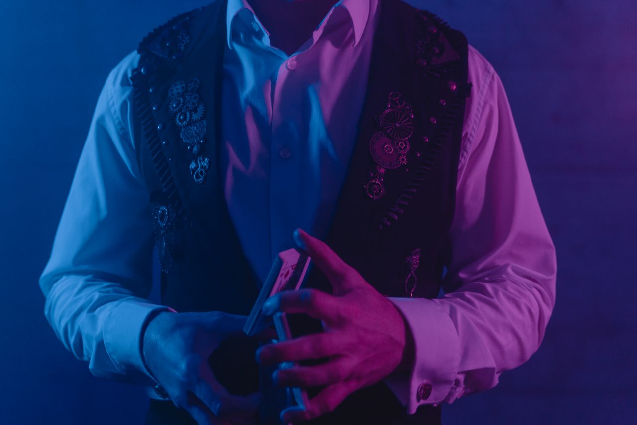 Crafting Captivating Headlines: Your awesome post title goes here Magician showcasing a card trick under vibrant purple and blue lights, creating a mysterious atmosphere.